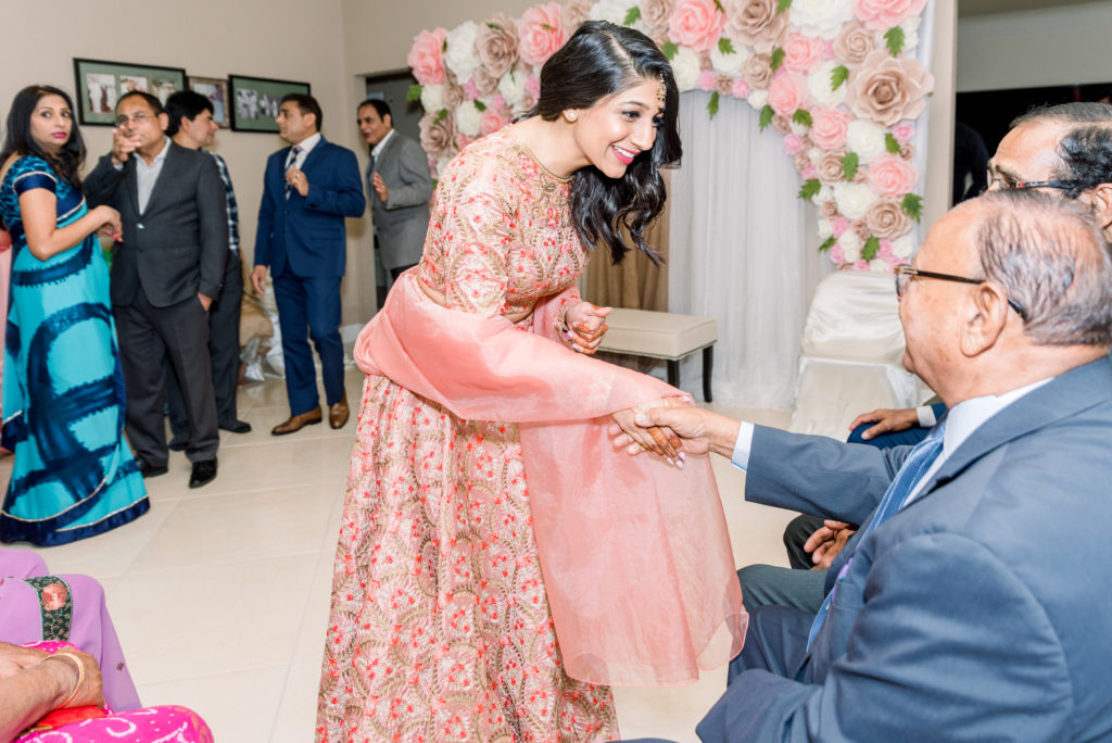 Bride greeting groom's family members at Indian engagement ceremony